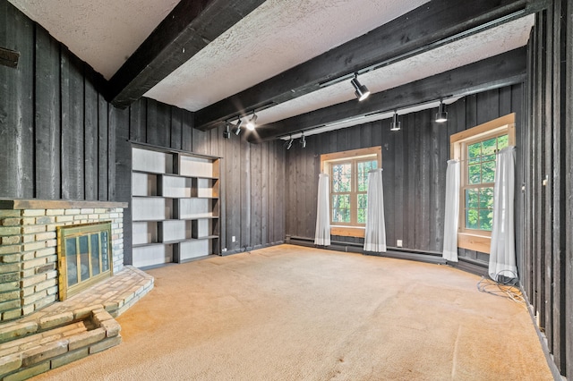 220 E Main St, Gaylord, MI 49735 - unfurnished living room featuring carpet flooring, track lighting, beam ceiling, wooden walls, and a baseboard heating unit