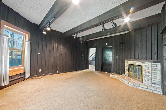 220 E Main St, Gaylord, MI 49735 - unfurnished living room featuring rail lighting, carpet, wood walls, a textured ceiling, and a brick fireplace