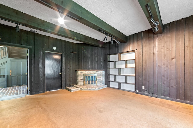 220 E Main St, Gaylord, MI 49735 - unfurnished living room with wood walls, track lighting, carpet floors, a textured ceiling, and beamed ceiling