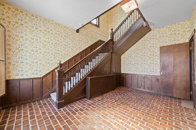 220 E Main St, Gaylord, MI 49735 - stairs featuring wallpapered walls, a wainscoted wall, and brick patterned flooring