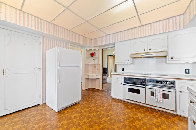 220 E Main St, Gaylord, MI 49735 - kitchen with white appliances, wallpapered walls, under cabinet range hood, white cabinetry, and light countertops