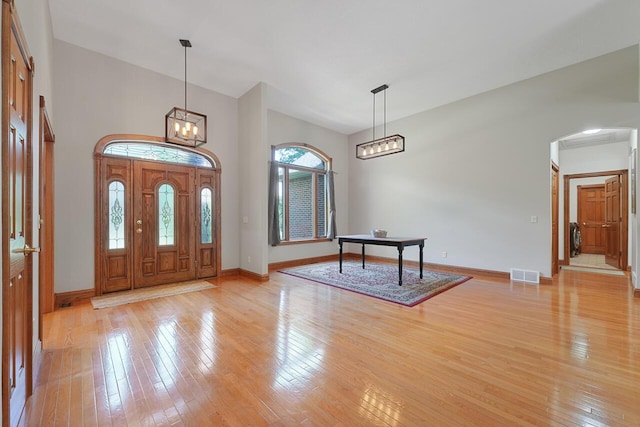142 Frisco Dr, Houghton Lake, MI 48629 - foyer with arched walkways, light wood finished floors, and a chandelier