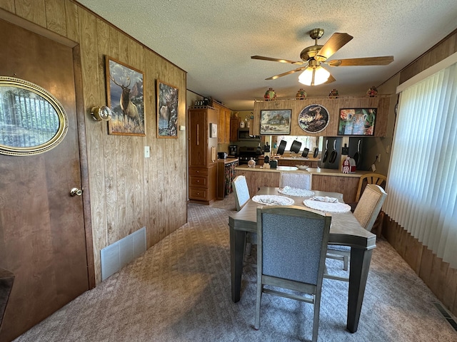 2585 M-33, Comins, MI 48619 - dining area featuring a ceiling fan, light carpet, wood walls, and a textured ceiling