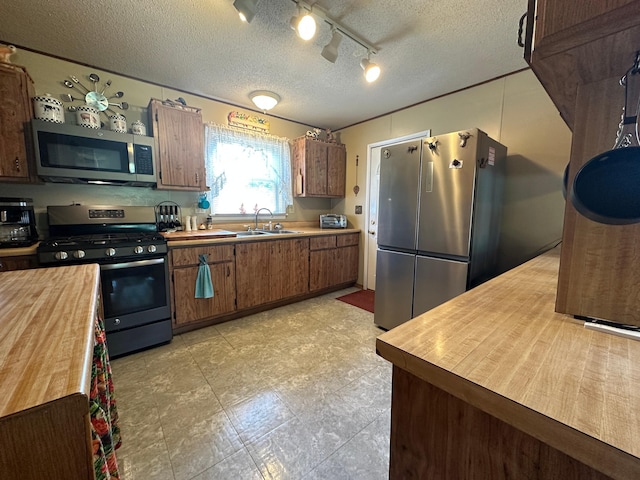 2585 M-33, Comins, MI 48619 - kitchen with stainless steel appliances, butcher block countertops, a textured ceiling, track lighting, and brown cabinets