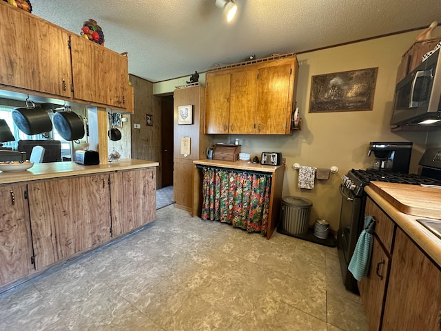 2585 M-33, Comins, MI 48619 - kitchen with gas stove, stainless steel microwave, a textured ceiling, brown cabinets, and light countertops