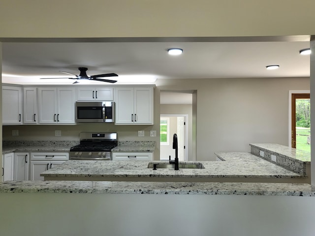 1251 Kingston Ave, Flint, MI 48507 - kitchen featuring stainless steel appliances, white cabinets, light stone countertops, and ceiling fan