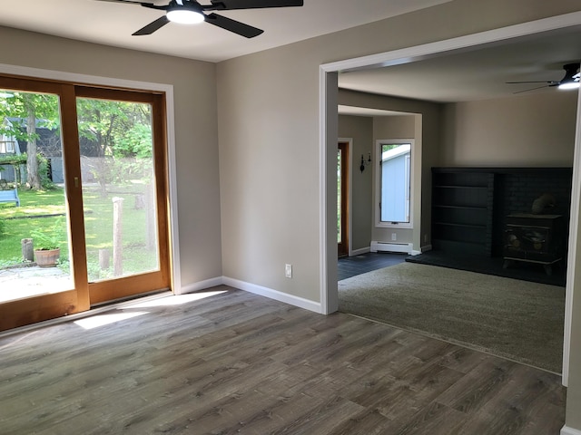 1251 Kingston Ave, Flint, MI 48507 - spare room with ceiling fan, baseboard heating, dark wood-style floors, and a fireplace with raised hearth