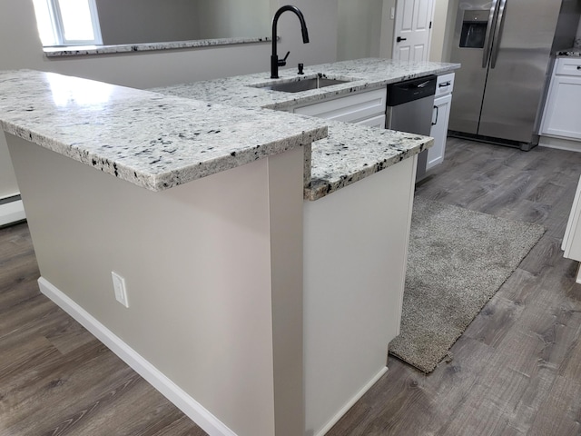 1251 Kingston Ave, Flint, MI 48507 - kitchen featuring stainless steel appliances, white cabinetry, wood finished floors, light stone countertops, and a large island