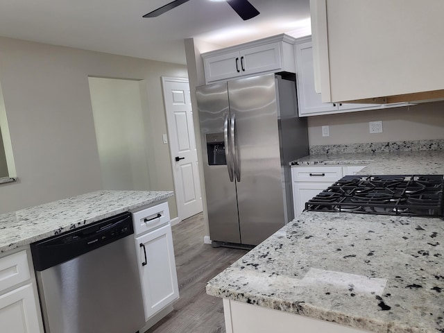 1251 Kingston Ave, Flint, MI 48507 - kitchen with stainless steel appliances, a ceiling fan, light wood-style floors, white cabinets, and light stone countertops