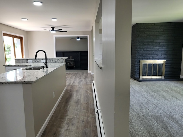 1251 Kingston Ave, Flint, MI 48507 - kitchen featuring a glass covered fireplace, a ceiling fan, baseboard heating, light stone counters, and open floor plan