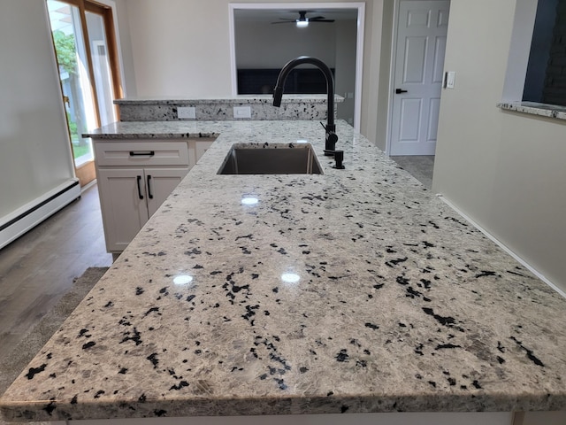 1251 Kingston Ave, Flint, MI 48507 - kitchen featuring light stone countertops, white cabinetry, a ceiling fan, wood finished floors, and a baseboard heating unit