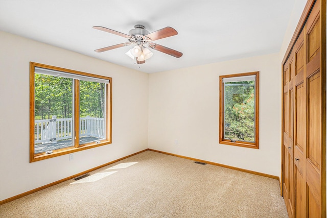 6296 Wolverine Trl, Gaylord, MI 49735 - unfurnished bedroom with multiple windows, a closet, light carpet, and ceiling fan