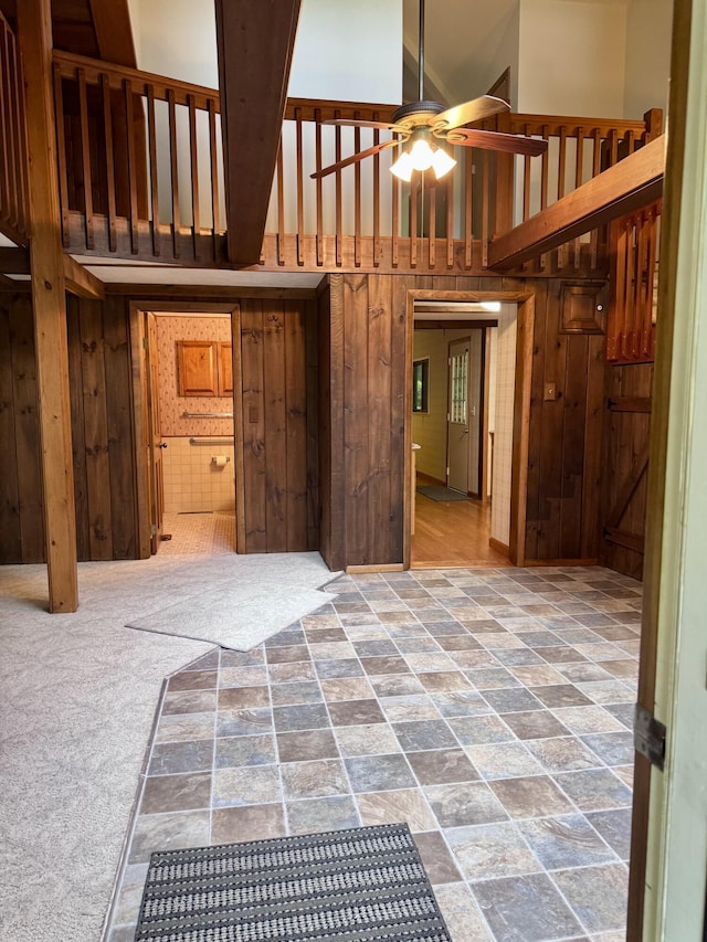 5200 Pine Grove Dr, Spruce, MI 48762 - unfurnished living room featuring wood walls, a towering ceiling, and ceiling fan