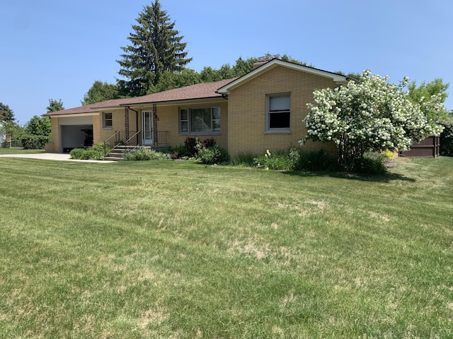 185 S June St, Alpena, MI 49707 - ranch-style home with a garage, brick siding, a front yard, and driveway