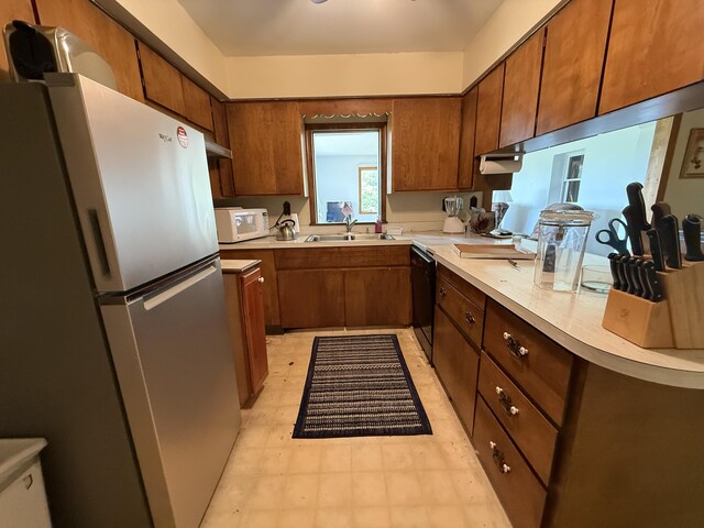 5913 M-33, Cheboygan, MI 49721 - kitchen featuring freestanding refrigerator, black dishwasher, light countertops, light floors, and brown cabinets