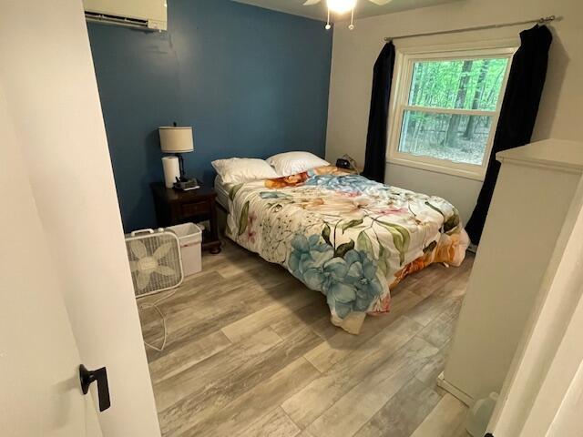 95 Caduca Ln, Roscommon, MI 48653 - bedroom featuring wood finished floors, an AC wall unit, and ceiling fan