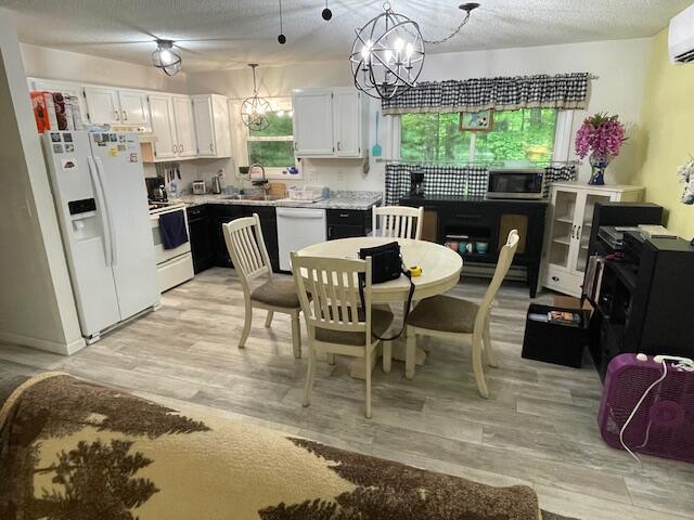 95 Caduca Ln, Roscommon, MI 48653 - kitchen featuring white appliances, an AC wall unit, light countertops, light wood-style floors, and a textured ceiling