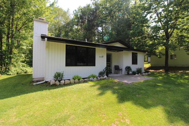211 Daytona Rd, Roscommon, MI 48653 - view of front facade with a chimney, a patio, and a front yard