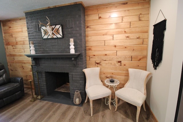 211 Daytona Rd, Roscommon, MI 48653 - sitting room featuring wood finished floors, wood walls, and a brick fireplace