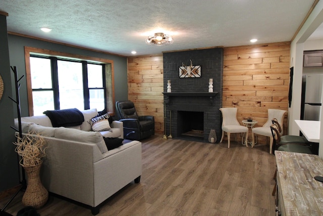 211 Daytona Rd, Roscommon, MI 48653 - living room with wood walls, wood finished floors, a textured ceiling, recessed lighting, and a fireplace