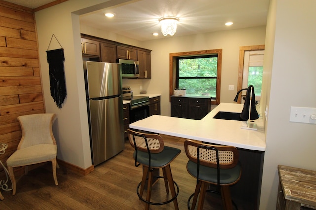 211 Daytona Rd, Roscommon, MI 48653 - kitchen with stainless steel appliances, dark wood finished floors, a breakfast bar, a peninsula, and light countertops