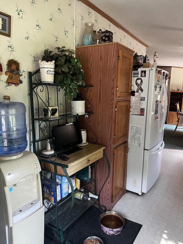 577 Wilderness Trl, Saint Helen, MI 48656 - kitchen featuring freestanding refrigerator, wallpapered walls, a textured ceiling, brown cabinetry, and ornamental molding