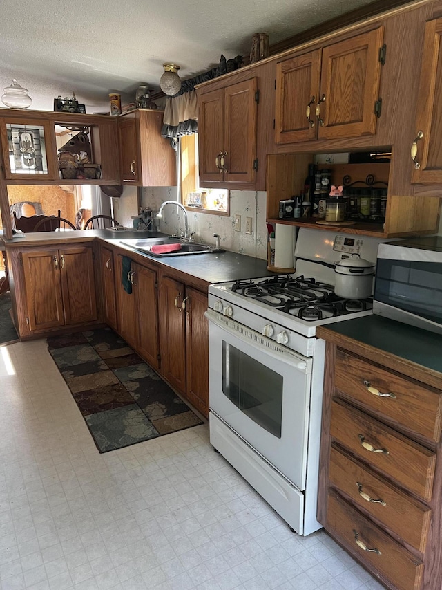 577 Wilderness Trl, Saint Helen, MI 48656 - kitchen featuring white range with gas stovetop, stainless steel microwave, light floors, brown cabinets, and a textured ceiling