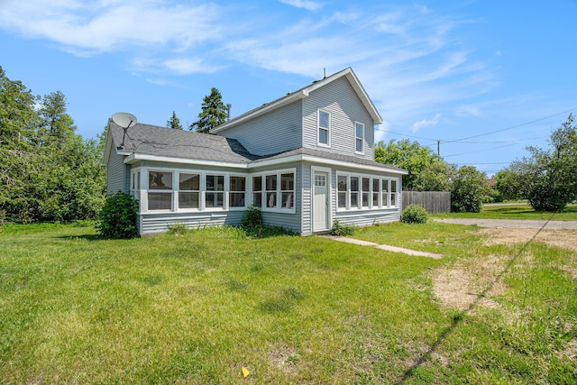 1014 Court St, Cheboygan, MI 49721 - rear view of house with a lawn, roof with shingles, dirt driveway, and a sunroom