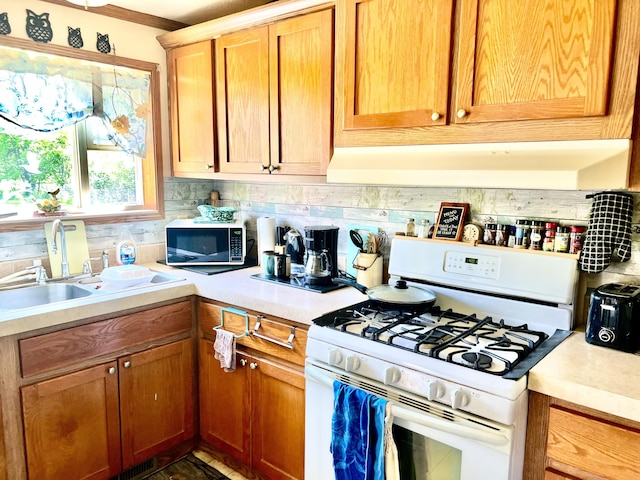 1604 Harrison Ave, Cheboygan, MI 49721 - kitchen featuring white range with gas cooktop, light countertops, under cabinet range hood, and decorative backsplash