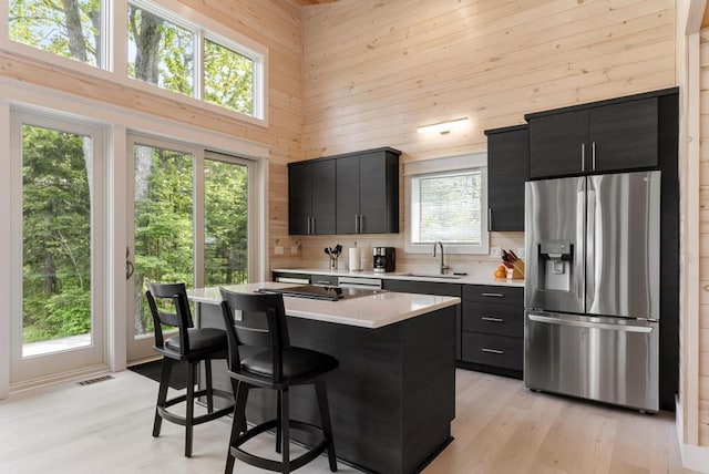 2960 W US-23 Hwy, Cheboygan, MI 49721 - kitchen with stainless steel refrigerator with ice dispenser, dark cabinetry, a towering ceiling, wooden walls, and light countertops