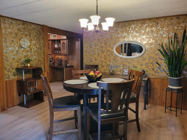 3211 S Partridge Point Rd, Alpena, MI 49707 - dining space featuring wallpapered walls, light wood finished floors, a wainscoted wall, a chandelier, and wood walls