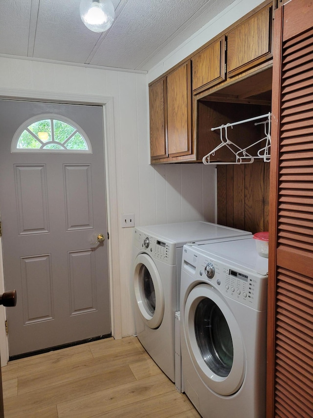3211 S Partridge Point Rd, Alpena, MI 49707 - washroom with cabinet space, washer and dryer, light wood-style flooring, and a textured ceiling