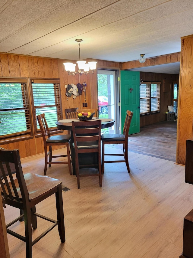 3211 S Partridge Point Rd, Alpena, MI 49707 - dining area featuring wooden walls, a chandelier, and light wood-style floors
