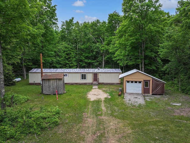 3178 Tobias Rd, Elmira, MI 49730 - view of front of house with an outbuilding, a detached garage, a view of trees, and a front yard