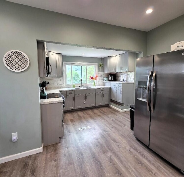510 W Baldwin St, Alpena, MI 49707 - kitchen with appliances with stainless steel finishes, gray cabinets, decorative backsplash, wood finished floors, and recessed lighting