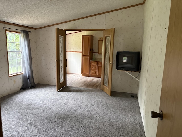 348 Lake Winyah Rd, Alpena, MI 49707 - carpeted empty room with ornamental molding, a textured ceiling, vaulted ceiling, and wallpapered walls