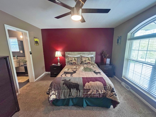 5514 N Bay Ct, Presque Isle, MI 49777 - carpeted bedroom featuring an accent wall, a ceiling fan, and ensuite bathroom