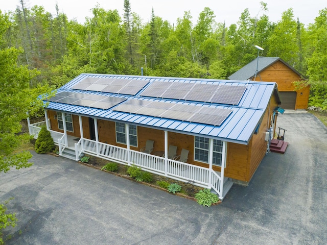 5514 N Bay Ct, Presque Isle, MI 49777 - view of front of house with a porch, roof mounted solar panels, a metal roof, and a forest view