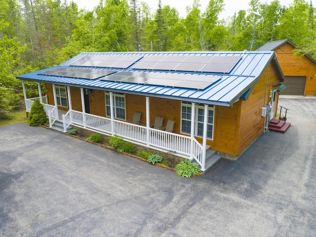 5514 N Bay Ct, Presque Isle, MI 49777 - view of front of property featuring covered porch, solar panels, and a metal roof