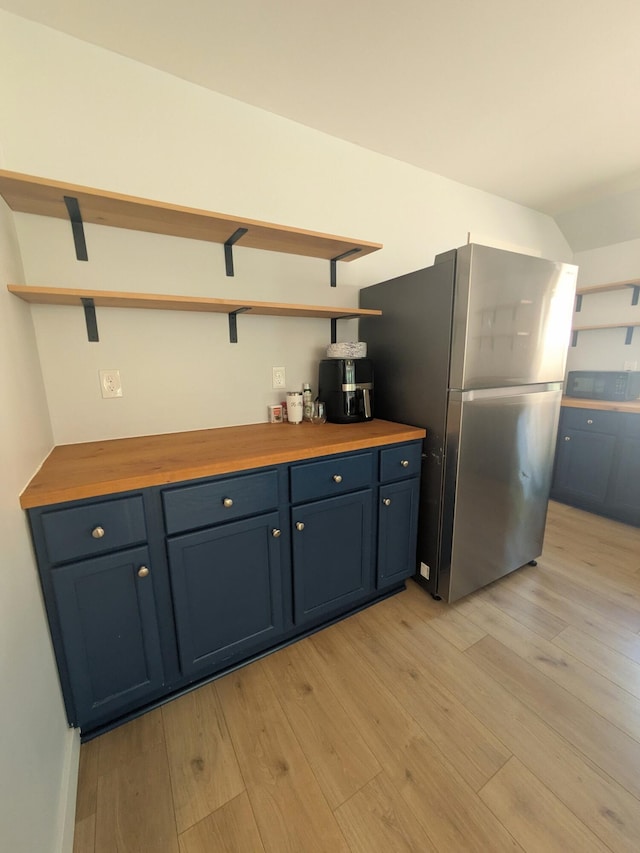 114 Pine St, Prudenville, MI 48651 - kitchen with open shelves, freestanding refrigerator, blue cabinets, light wood-style floors, and wood counters