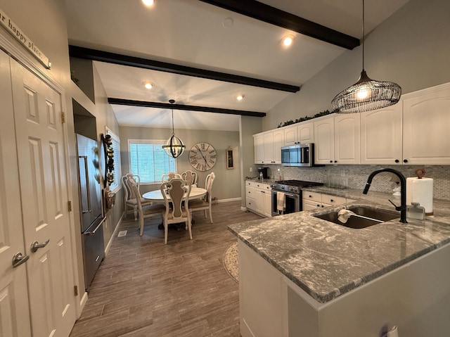 108 Bourbon St, Roscommon, MI 48653 - kitchen featuring premium appliances, dark stone countertops, white cabinets, decorative backsplash, and wood finished floors