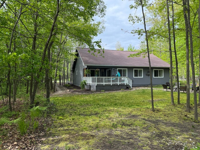 108 Bourbon St, Roscommon, MI 48653 - view of front facade featuring covered porch, a front lawn, a fire pit, and a shingled roof