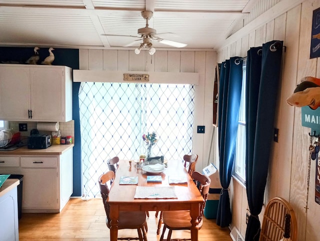 223 Mallard Ave, Houghton Lake, MI 48629 - dining space with light wood-style floors, a ceiling fan, a wooden ceiling with exposed beams, and wooden walls