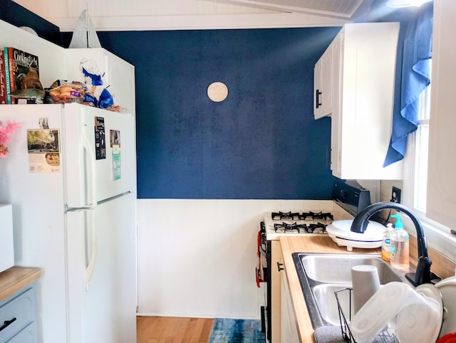 223 Mallard Ave, Houghton Lake, MI 48629 - kitchen with freestanding refrigerator, range with gas stovetop, wood finished floors, and light countertops