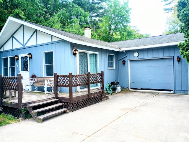 223 Mallard Ave, Houghton Lake, MI 48629 - view of front facade with concrete driveway, a garage, a chimney, roof with shingles, and a wooden deck