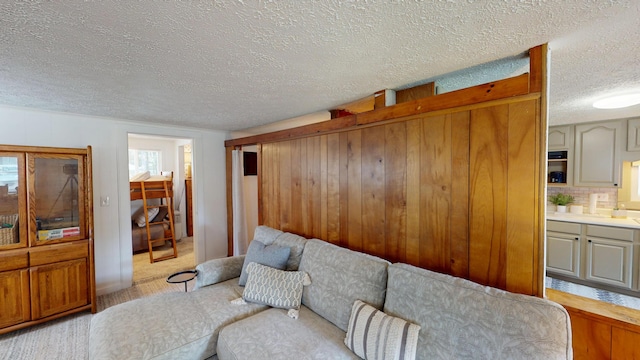 213 Devonshire Dr, Prudenville, MI 48651 - living room with a textured ceiling, wood walls, and light carpet