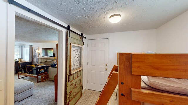 213 Devonshire Dr, Prudenville, MI 48651 - bedroom with a barn door, a textured ceiling, and light carpet