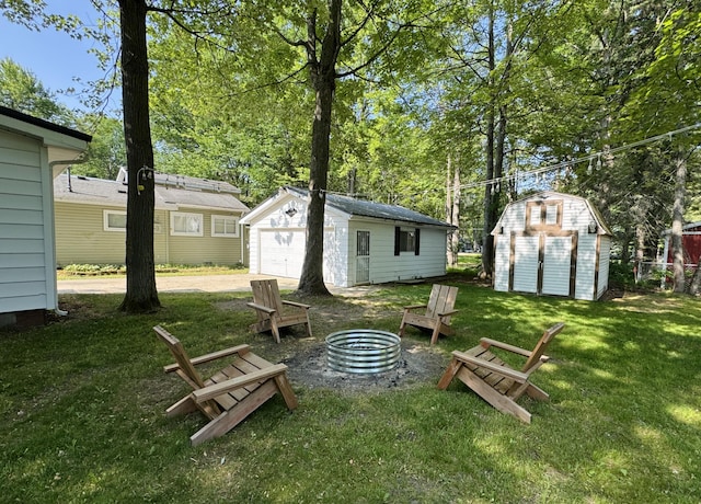 213 Devonshire Dr, Prudenville, MI 48651 - view of green lawn with an outdoor fire pit, an outdoor structure, a garage, and driveway