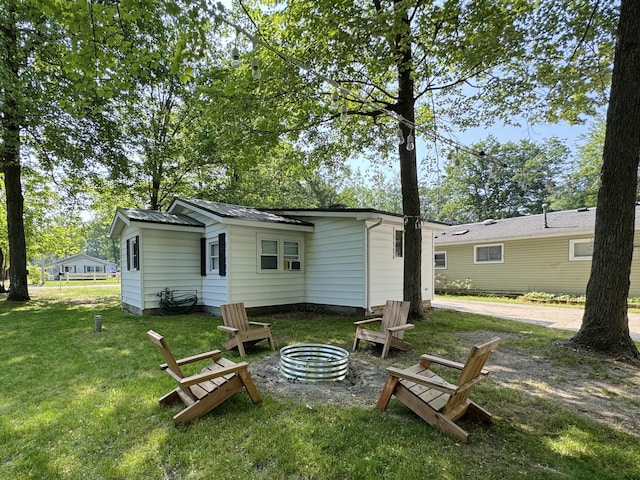 213 Devonshire Dr, Prudenville, MI 48651 - back of house featuring an outdoor fire pit and a lawn