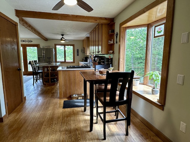 7984 US-23, Cheboygan, MI 49721 - dining space featuring a ceiling fan, light wood-style floors, beamed ceiling, and a textured ceiling